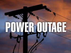 A picture of a power pole with lines coming off of it with "POWER OUTAGE" in white lettering.