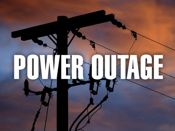 A picture of a power pole with lines coming off of it with "POWER OUTAGE" in white lettering.